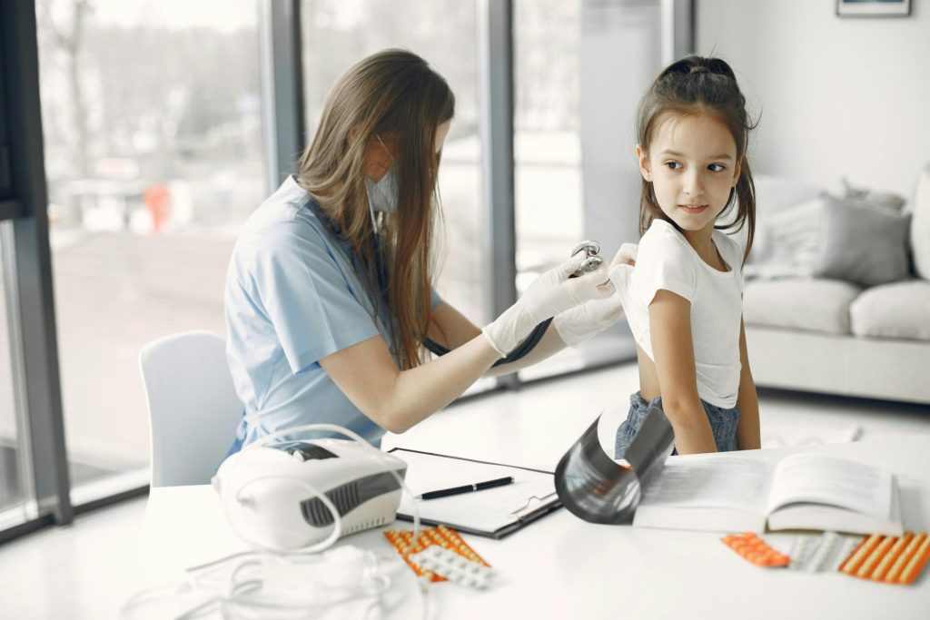 Young girl in clinic receiving a checkup from a female doctor with stethoscope.